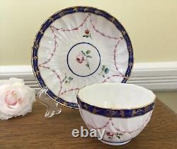 Bol à thé et soucoupe en porcelaine de la Couronne Derby antique de 1778, peints à la main avec des motifs floraux et une bordure en cobalt.