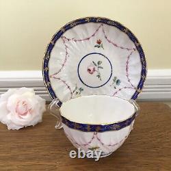 Bol à thé et soucoupe en porcelaine de la Couronne Derby antique de 1778, peints à la main avec des motifs floraux et une bordure en cobalt.