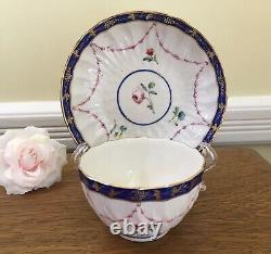 Bol à thé et soucoupe en porcelaine de la Couronne Derby antique de 1778, peints à la main avec des motifs floraux et une bordure en cobalt.