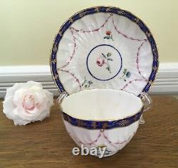 Bol à thé et soucoupe en porcelaine de la Couronne Derby antique de 1778, peints à la main avec des motifs floraux et une bordure en cobalt.